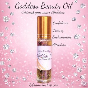 May include: A clear glass roll-on bottle with a gold cap, labelled "Goddess Beauty Oil." The label includes the text "Unleash your inner Goddess," "Confidence," "Luxury," "Enchantment," and "Attention." The background is pink with diamond-shaped sparkles.