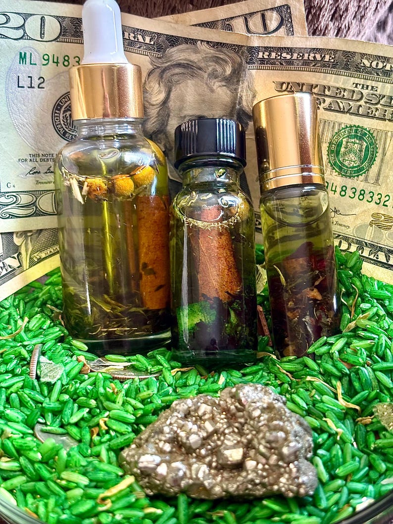 Pode incluir: Tr&ecirc;s frascos de vidro cheios de l&iacute;quido e bot&acirc;nicos, com tampas douradas e pretas. Os frascos est&atilde;o sobre uma cama de arroz verde e rodeados por notas de vinte d&oacute;lares americanos. Uma pedra de pirite est&aacute; em primeiro plano.