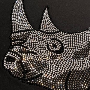 Op de afbeelding: Een zwart T-shirt met een neushoornontwerp van strass. De strass zijn zilver en zwart.