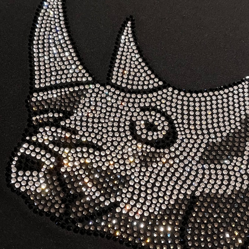 Op de afbeelding: Een zwart T-shirt met een neushoornontwerp van strass. De strass zijn zilver en zwart.