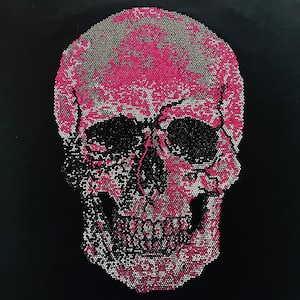 May include: A detailed skull design, rendered in a mosaic style, dominates the image. The skull's cranium is a vibrant pink, contrasted by black eye sockets and a black background. The design is composed of small, closely-packed dots.