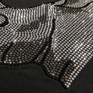 Op de afbeelding: Zwarte stof met een ontwerp van zilveren en zwarte strass in een geometrisch patroon.