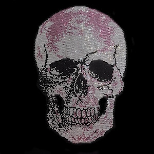 Può includere: Un teschio fatto di strass, con strass rosa e bianchi che formano il teschio e strass neri che formano le orbite.