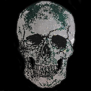 May include: A black and white skull design made of rhinestones. The skull is outlined in green rhinestones.