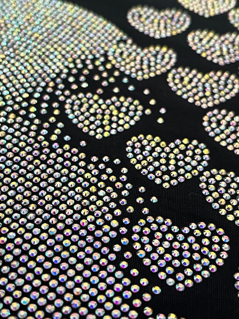 May include: A black fabric background with a skull design made of iridescent rhinestones.