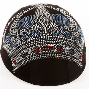 May include: A black helmet with a crown design made of rhinestones. The crown is decorated with clear, blue, and red rhinestones.