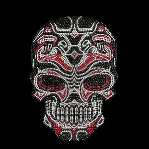 May include: A black and white skull with red accents, made of rhinestones. The skull is detailed with intricate patterns and designs.