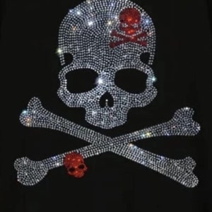 May include: A black t-shirt featuring a rhinestone skull and crossbones design. The skull and crossbones are outlined in red rhinestones.