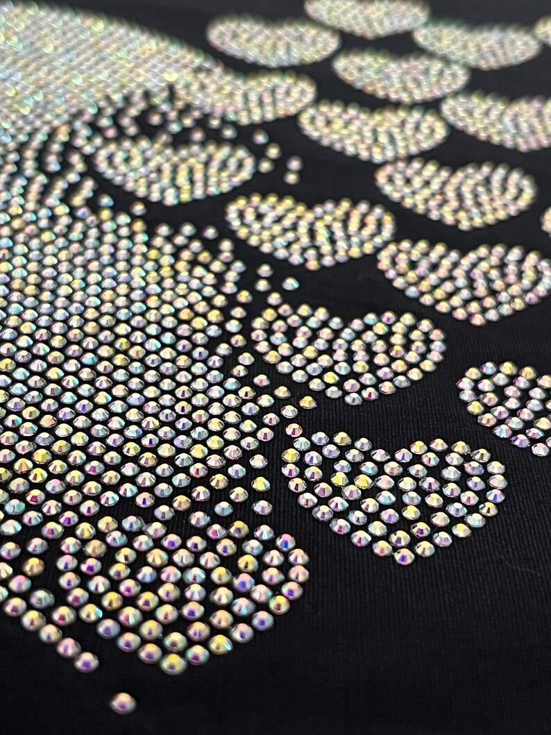 May include: A black fabric background with a design of iridescent rhinestones in the shape of a footprint.