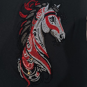 May include: A black fabric with a red and silver rhinestone horse head design. The horse's mane is black and the design is intricate.