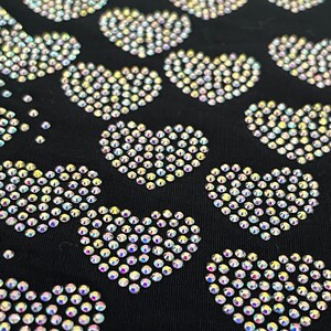 May include: Black fabric with a pattern of iridescent rhinestones arranged in the shape of hearts.