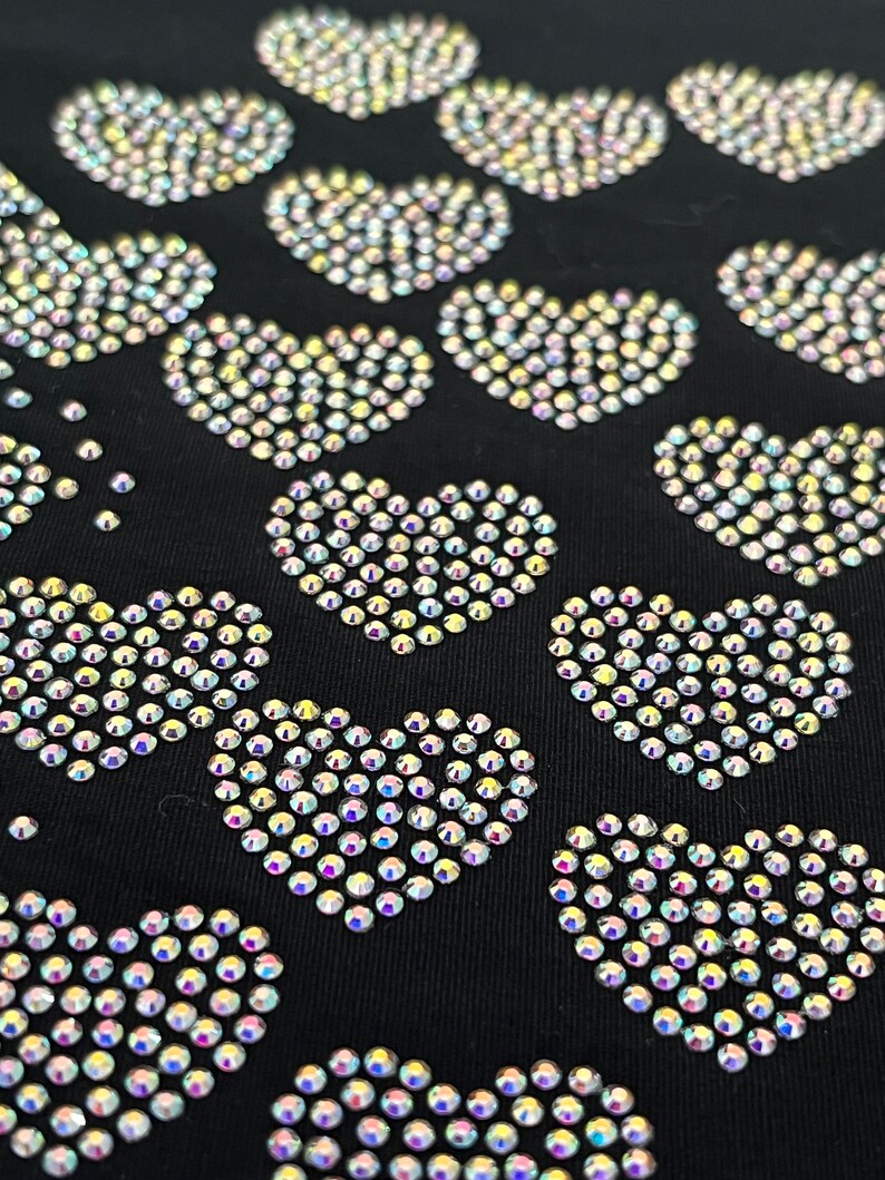 May include: Black fabric with a pattern of iridescent rhinestones arranged in the shape of hearts.