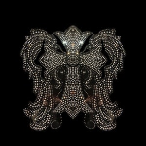 May include: A silver rhinestone cross design with intricate details. The cross is surrounded by two symmetrical floral patterns, also made of rhinestones.