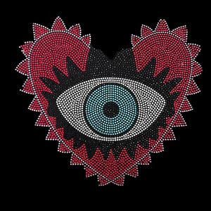 May include: A red heart-shaped design with a black eye in the center. The eye is made of rhinestones and has a blue iris. The heart is also made of rhinestones.