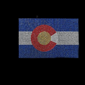 May include: A blue, white, and red Colorado state flag made of rhinestones. The flag features a large, circular, red, white, and yellow symbol in the center.