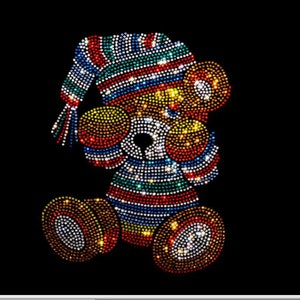 May include: A colorful, sparkly, rhinestone-covered teddy bear wearing a hat. The bear is in a standing position with its arms raised. The bear is made of rhinestones in shades of red, orange, yellow, green, blue, and purple.