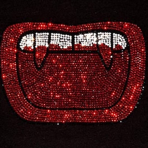 Könnte beinhalten: Rotes und weißes Strass-Vampirzahndesign. Die Zähne sind schwarz umrandet und das Design ist vor einem schwarzen Hintergrund.