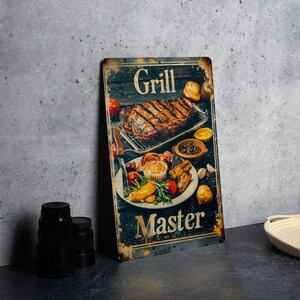 May include: A vintage-style metal sign with a rustic background featuring a grilled steak, vegetables, and the text "Grill Master".
