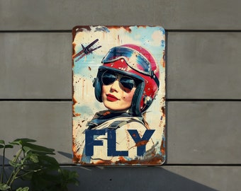 May include: A vintage-style metal sign featuring a woman wearing a red aviator helmet and goggles. The sign has a distressed, rusty look and the word "FLY" is printed in blue letters.
