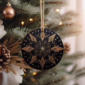 May include: A black and gold Christmas ornament with a geometric star design. The ornament is round and has a string for hanging.
