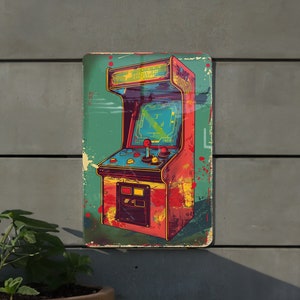 May include: A vintage-style metal sign featuring a colorful illustration of an arcade game. The game has a red cabinet with a blue screen and yellow buttons. The sign has a distressed look with paint splatters and a faded background.
