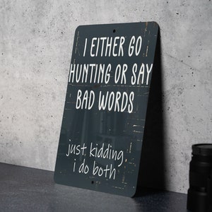 May include: A black metal sign with white text that reads "I either go hunting or say bad words. Just kidding, I do both."