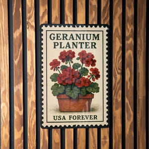 May include: A rectangular sign with a stamp design featuring a geranium planter. The sign reads "GERANIUM PLANTER" at the top and "USA FOREVER" at the bottom. The background is a wooden wall with vertical brown and black stripes.