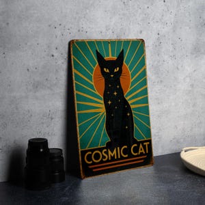 May include: A vintage-style metal sign featuring a black cat silhouette with star details, set against a teal and gold sunburst design. The words "COSMIC CAT" are displayed at the bottom. The sign has a distressed, aged appearance.