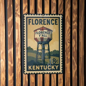 A vintage-style metal sign with the text "FLORENCE" and "FLORENCE Y'ALL" is displayed on a wooden wall.