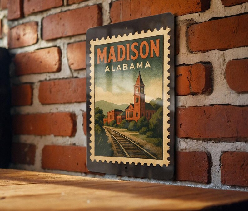 A vintage-style metal sign with the text "MADISON ALABAMA" displayed on a brick wall.