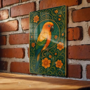 May include: A rectangular wall art piece featuring a vibrant parrot illustration. The parrot has orange, yellow, green, and blue plumage, perched on a branch within a floral design. The background is teal with orange flowers.