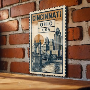 May include: A vintage-style metal sign featuring a cityscape of Cincinnati, Ohio, USA, with a bridge and skyline. The sign has a postage stamp design with the city name and state. The color palette includes shades of blue, beige, and orange.