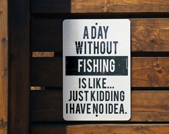 May include: A white sign with black text on a wooden background. The sign reads "A day without fishing is like... Just kidding, I have no idea."