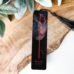 May include: Black bookmark with a red line down the center and a woman's face on the left side. The bookmark has a black tassel and the word "Murder" at the bottom.