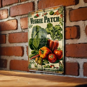 May include: A vintage-style metal sign with the text "Veggie Patch" in green and white lettering. The sign features a colorful illustration of various vegetables, including a green cabbage, red peppers, and tomatoes.