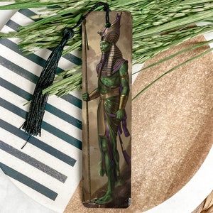 May include: A bookmark featuring an illustration of an Egyptian god with green skin, a gold headdress, and a staff. The background is a brown and gold color.
