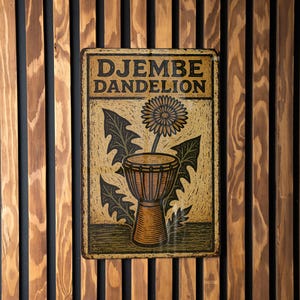 May include: A rectangular metal sign with the words "DJEMBE DANDELION" in a vintage style. The sign features a dandelion flower and a djembe drum illustration in shades of brown, black, and yellow. The sign is mounted on a wooden slatted wall.