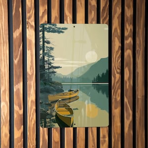 May include: Metal sign featuring a serene lake scene with two yellow canoes, mountains, and a large sun. The artwork has a vintage aesthetic, with muted greens and yellows. The sign is mounted on a wooden slat wall.