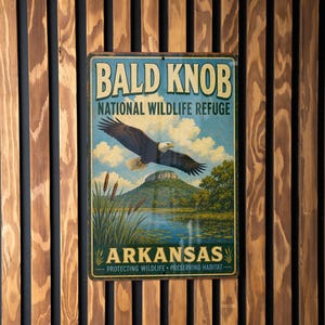 May include: A vintage-style metal sign for Bald Knob National Wildlife Refuge in Arkansas. The sign features an eagle in flight over a lake and mountain, with text that reads "Protecting Wildlife, Preserving Habitat."