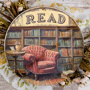 May include: A round wooden sign with a painted image of a library with bookshelves and a red armchair. The sign says "READ" in gold letters.