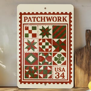 May include: Rectangular cream-colored sign with a red border and the word "PATCHWORK" at the top. The sign features a patchwork design with red and green geometric patterns. The text "USA 34" is at the bottom. The sign is displayed on a wooden surface.