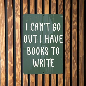 May include: A green metal sign with white text that reads "I can't go out. I have books to write."