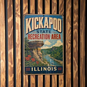 May include: A vintage-style metal sign for Kickapoo State Recreation Area in Illinois, featuring a scenic landscape with a river, rock formations, and vibrant red flowers. The sign is mounted on a wooden slatted wall.
