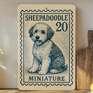 May include: A rectangular sign featuring a vintage-style illustration of a Sheepadoodle dog. The sign has a postage stamp design with the words "SHEEPADOODLE 20 MINIATURE" in a dark teal color. The dog is depicted in black and white.