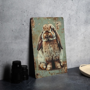 May include: A metal sign with a distressed, rusty look featuring a brown and white rabbit with long ears. The rabbit is looking directly at the viewer with a serious expression.