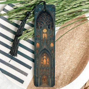 May include: A detailed bookmark featuring a gothic cathedral design with a tree silhouette. The bookmark has a dark blue and gold color scheme, with a black tassel. The bookmark is approximately 7 inches long.