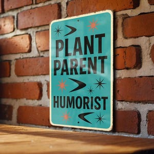May include: A vintage-style teal metal sign with the words "PLANT PARENT HUMORIST" in black, accented with starburst and arrow designs. The sign is mounted on a brick wall.