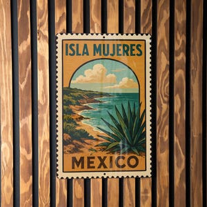 May include: A rectangular sign featuring a vintage travel poster design for Isla Mujeres, Mexico. The poster depicts a coastal scene with turquoise water, a sandy beach, and lush green vegetation. The sign is framed by a decorative border and mounted on a wooden slat wall.