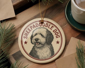 May include: Cream-colored round ornament featuring a Sheepadoodle dog illustration. The dog is depicted in black and white with a red border and the words "SHEEPADOODLE DOG" in a circular design. Includes a gold string for hanging.