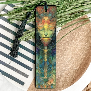 May include: A wooden bookmark with a colorful illustration of a woman's face surrounded by intricate designs. The bookmark has a black tassel.